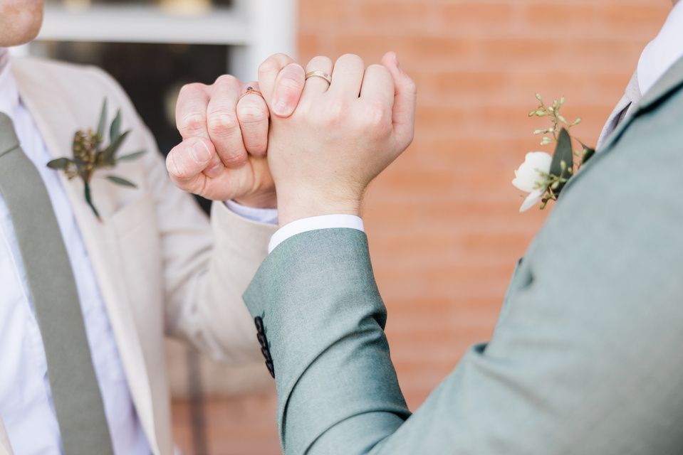 Two Grooms in Suits Doing Pinky Promise on Their Wedding